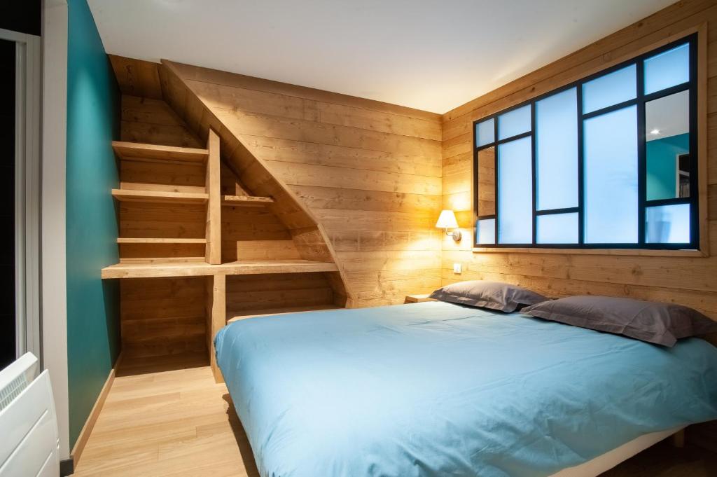 - une chambre avec un lit bleu et un escalier dans l'établissement Le Refuge, à Gérardmer