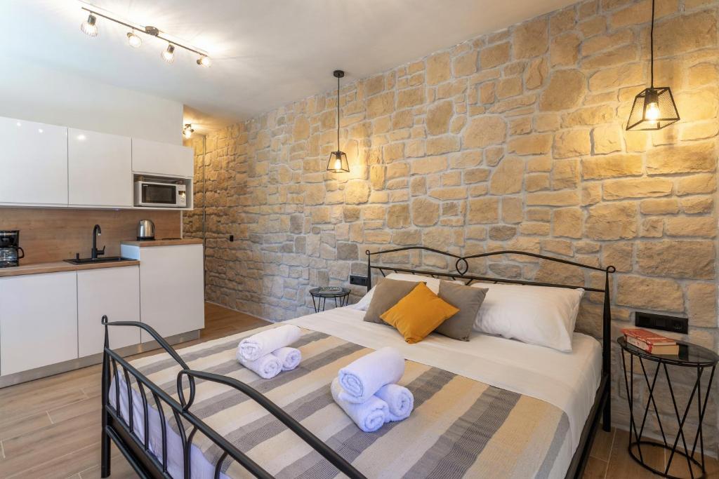 a bedroom with a bed and a stone wall at TEONA Luxury Studio Apartment with jacuzzi and garden view in Sali