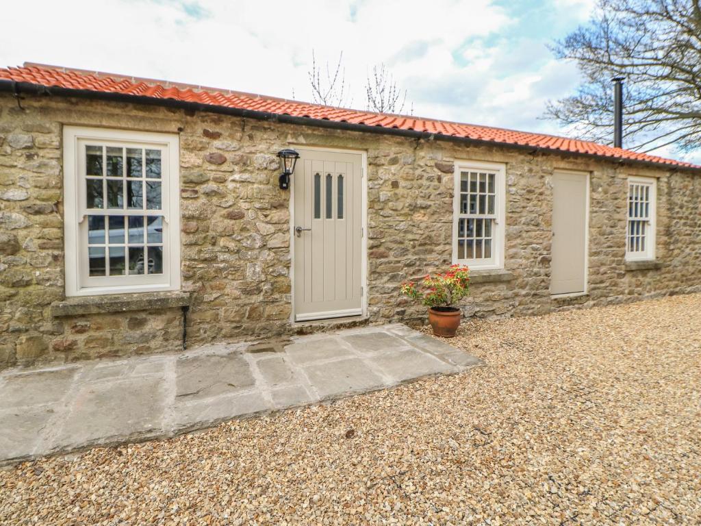 a stone cottage with a white door and windows at The Netty in Richmond