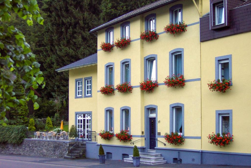 a yellow building with flower boxes on it at Hotel Lindenhof in Monschau