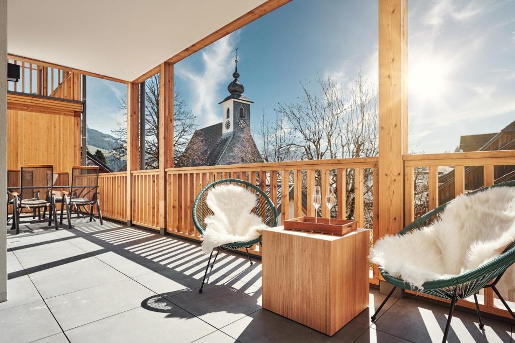 einen Balkon mit Stühlen und eine Kirche im Hintergrund in der Unterkunft die Tauplitz Lodges - Alm Lodge A2 by AA Holiday Homes in Tauplitz