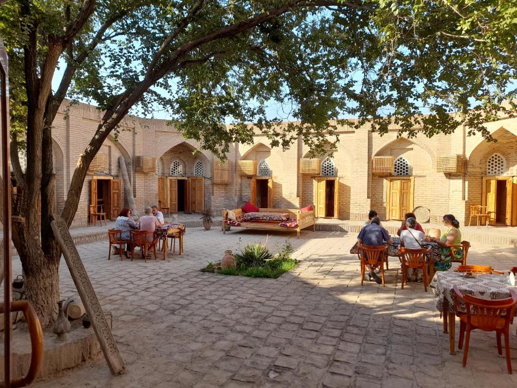 a group of people sitting at tables in a courtyard at Caravan Sarai in Khiva