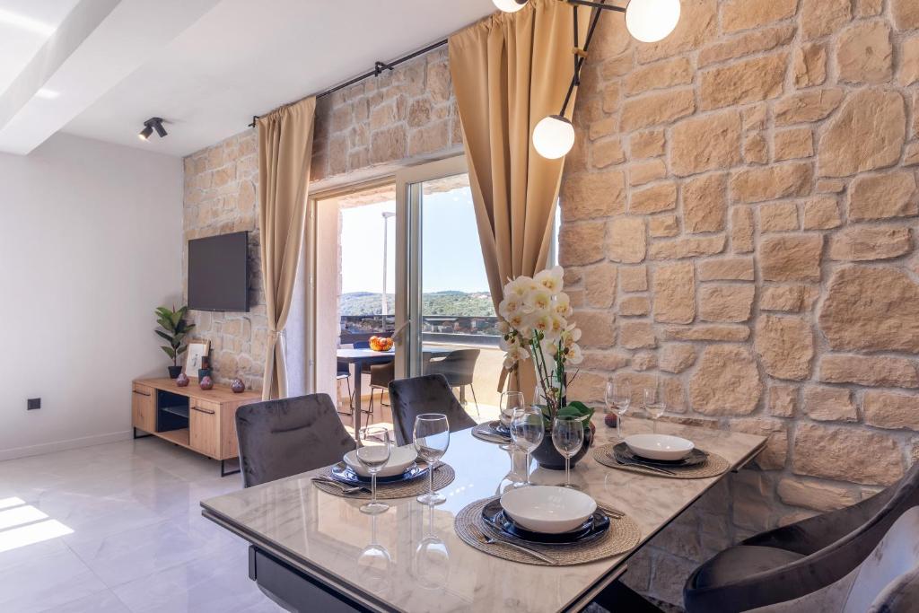 una sala da pranzo con tavolo e parete in pietra di TEONA Luxury Apartment with jacuzzi and terrace sea view a Sali (Sale)