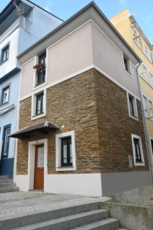 a brick building with a brown door and stairs at O Recuncho de Celia in Foz