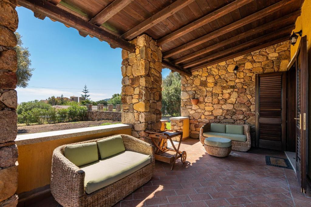 Villa Licia San Pietro في Cala Sinzias: فناء مع أثاث الخوص وجدار حجري