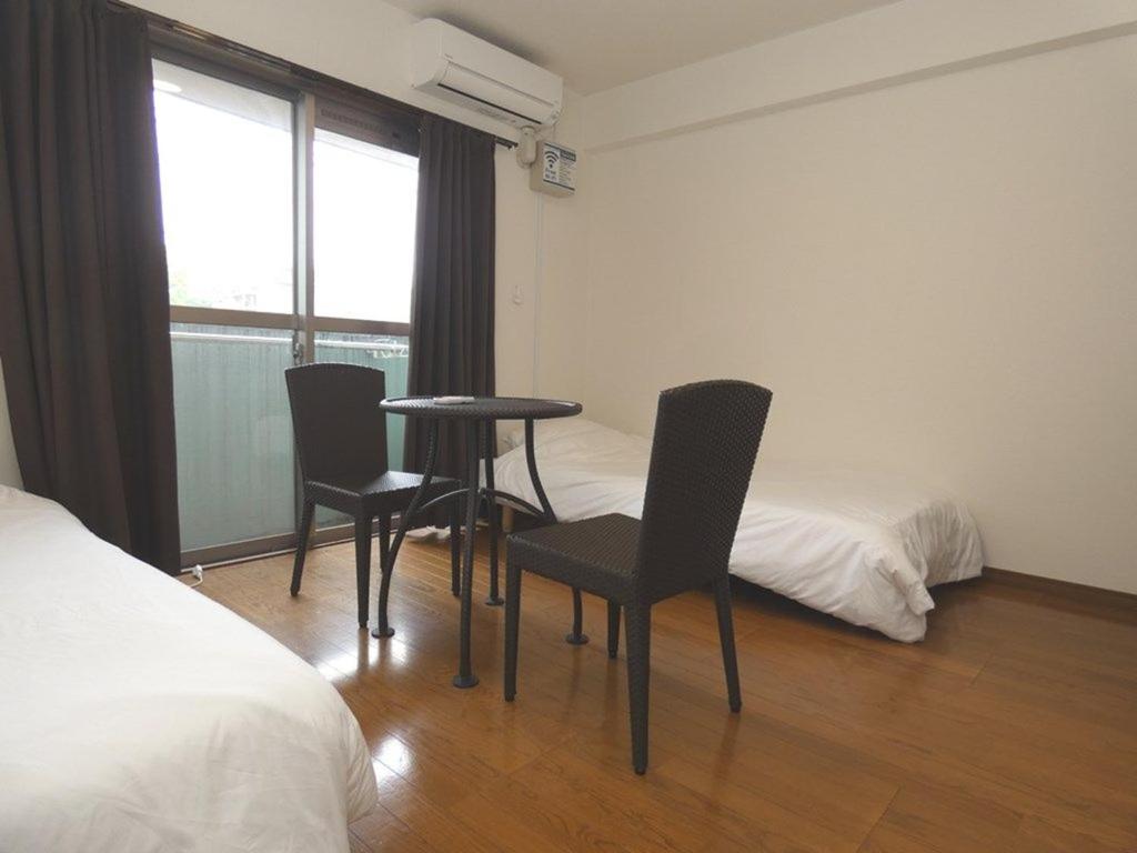 ein Schlafzimmer mit einem Tisch, Stühlen und einem Bett in der Unterkunft AO Dazaifu / Vacation STAY 61720 in Chikushino