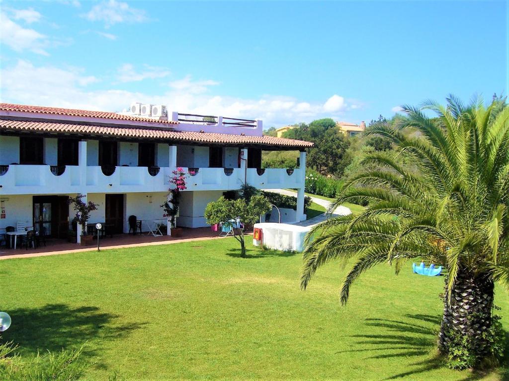 a building with a palm tree next to a yard at White Sand Residence in Murta Maria