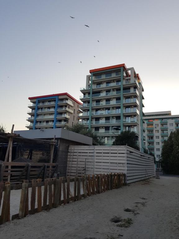 two tall buildings in front of a beach with a fence at Fancy Beach Apartment in Mamaia