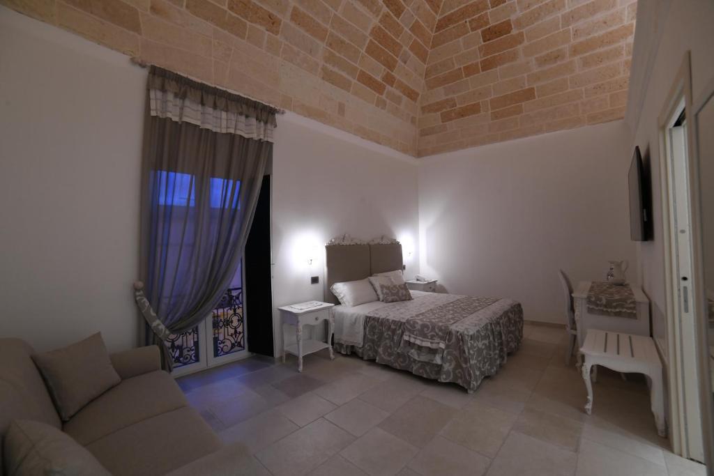 um quarto com uma cama e um sofá num quarto em PLAZACARRISI HOTEL & SPA em Cellino San Marco