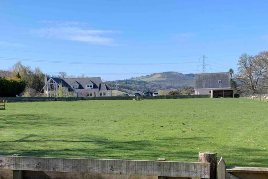 un gran campo de césped verde con casas en el fondo en The Nest - Near Inverness & Loch Ness en Inverness