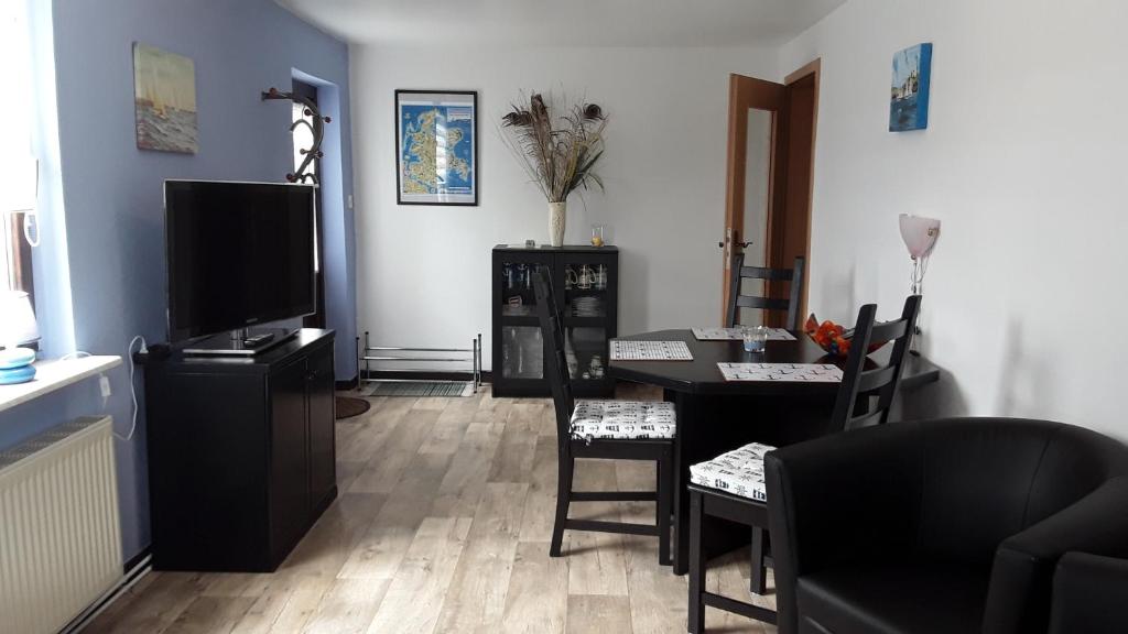 ein Wohnzimmer mit einem TV und einem Tisch mit Stühlen in der Unterkunft Ferienwohnung Putbus in Putbus