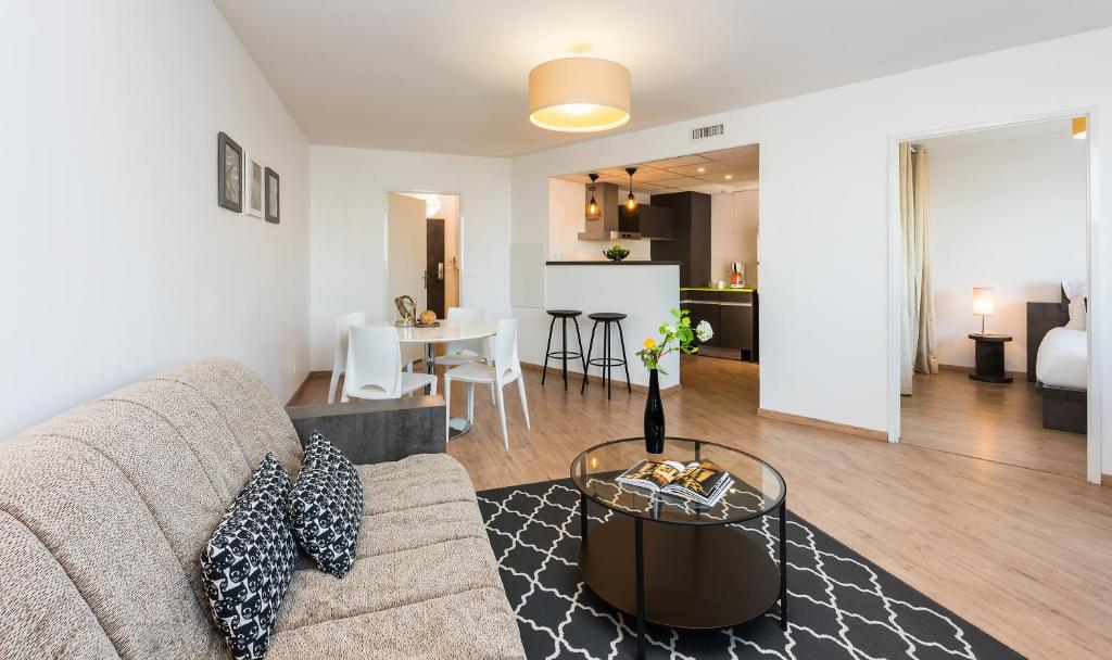 a living room with a couch and a table at Ténéo Apparthotel Talence Arthena in Talence