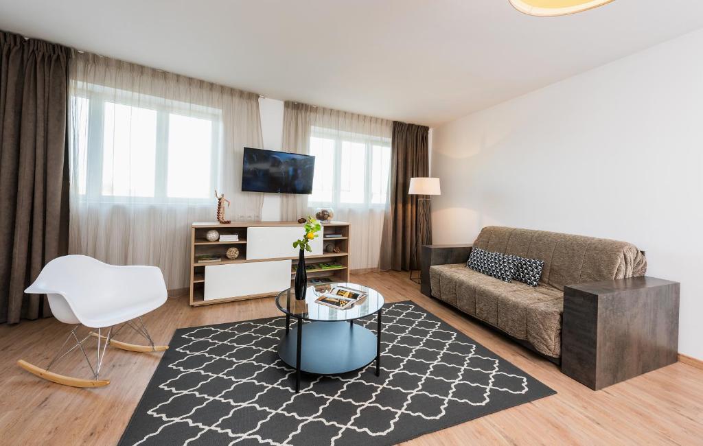 a living room with a couch and a table at Ténéo Apparthotel Talence Arthena in Talence