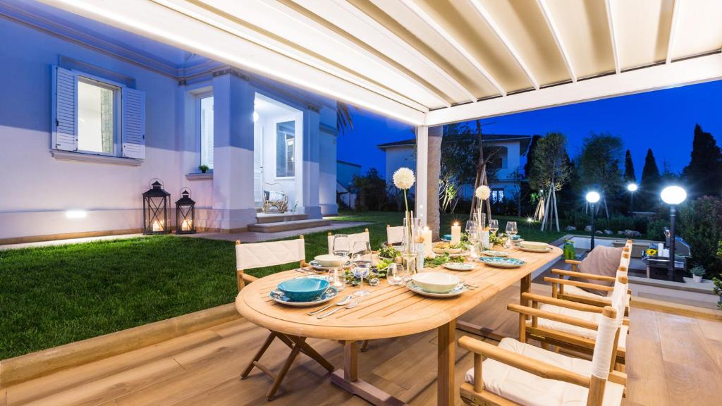 - une table à manger sous une pergola dans l'arrière-cour dans l'établissement Villa Sole Al Molino A Vento 8, Emma Villas, à Rosignano Marittimo