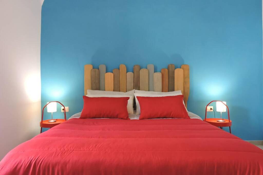 1 cama roja con 2 almohadas rojas y pared azul en Blue Sail Apartment en Termoli