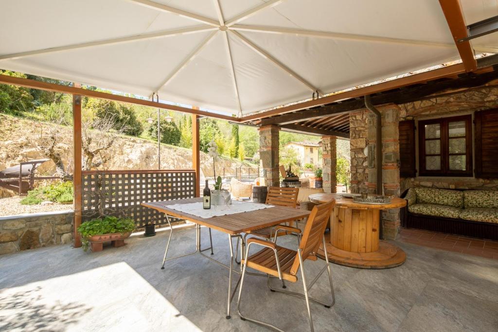 patio ze stołem i krzesłami pod białym parasolem w obiekcie Villa Vepri by Mmega w mieście Cennina