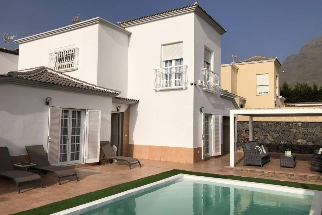 a white house with a swimming pool in front of it at Villa Vanesa luxury private villa with a heated pool, 4 bedrooms and 4 bathrooms in Adeje