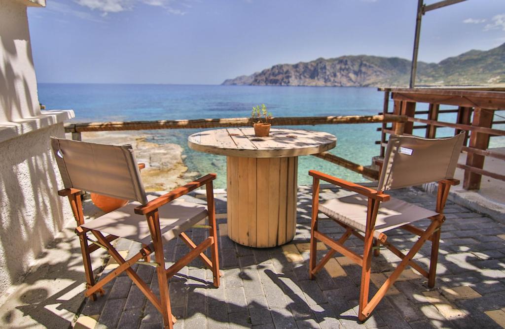 einen Tisch und 2 Stühle auf einer Terrasse mit Meerblick in der Unterkunft The Wave House in Mochlos
