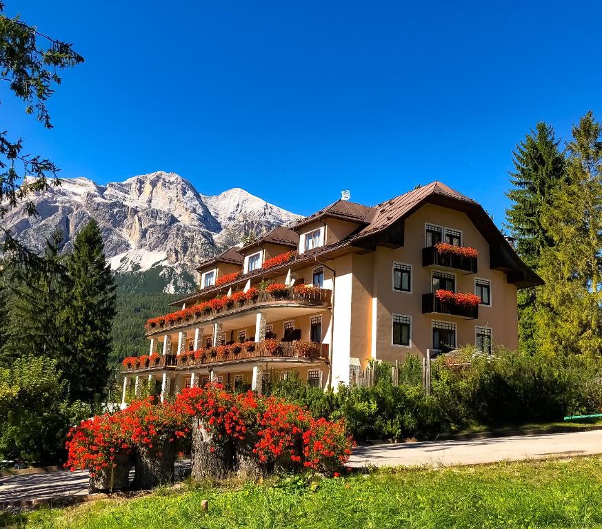 ein großes Gebäude mit Blumen vor einem Berg in der Unterkunft Boutique Hotel Villa Blu Cortina D'Ampezzo in Cortina d'Ampezzo