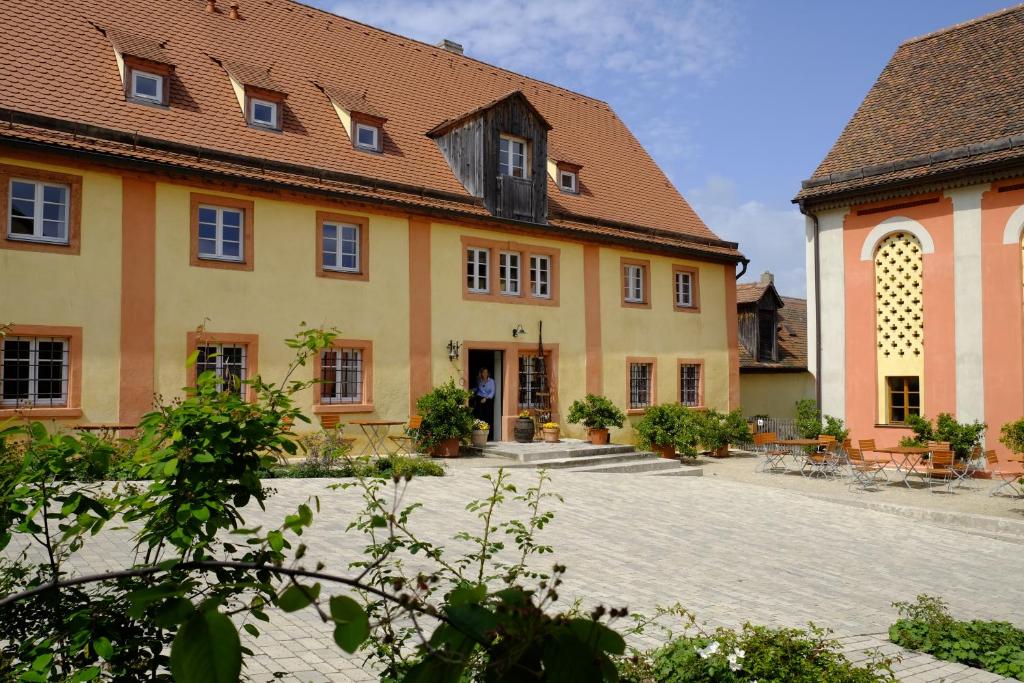 a large yellow building with a brick courtyard at Gentner - Hotel garni in Gnotzheim