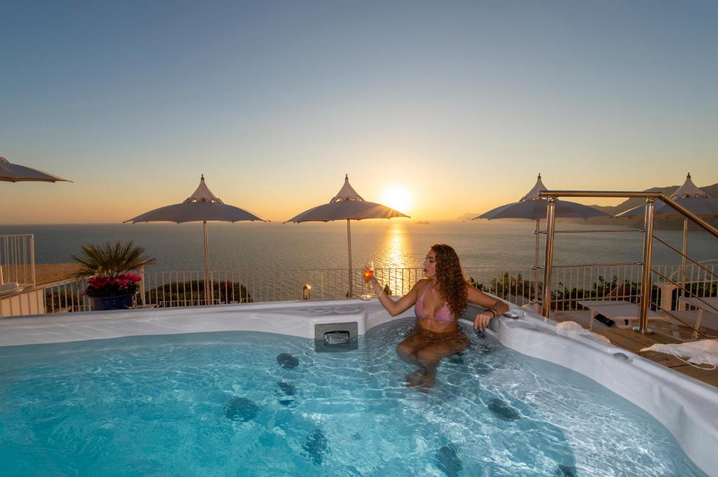 uma mulher numa piscina com um copo de vinho em Luxury Villa Malika - Great View on Capri&Positano em Praiano