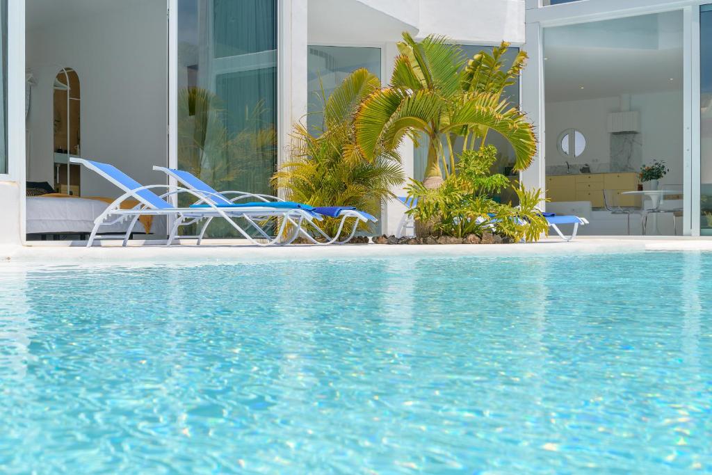 two chairs and a swimming pool in front of a house at AQUABLANCA Suite Love Deluxe en Punta Mujeres in Punta de Mujeres