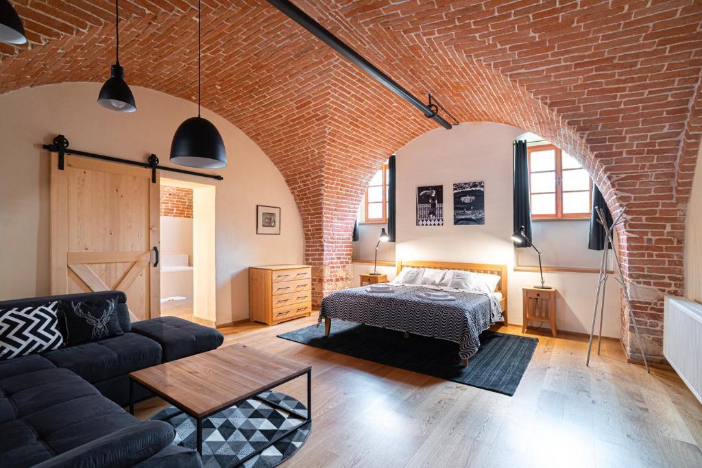 - un salon avec un lit et un mur en briques dans l'établissement NA KNÍŽECÍ CESTĚ VALTICE, à Valtice