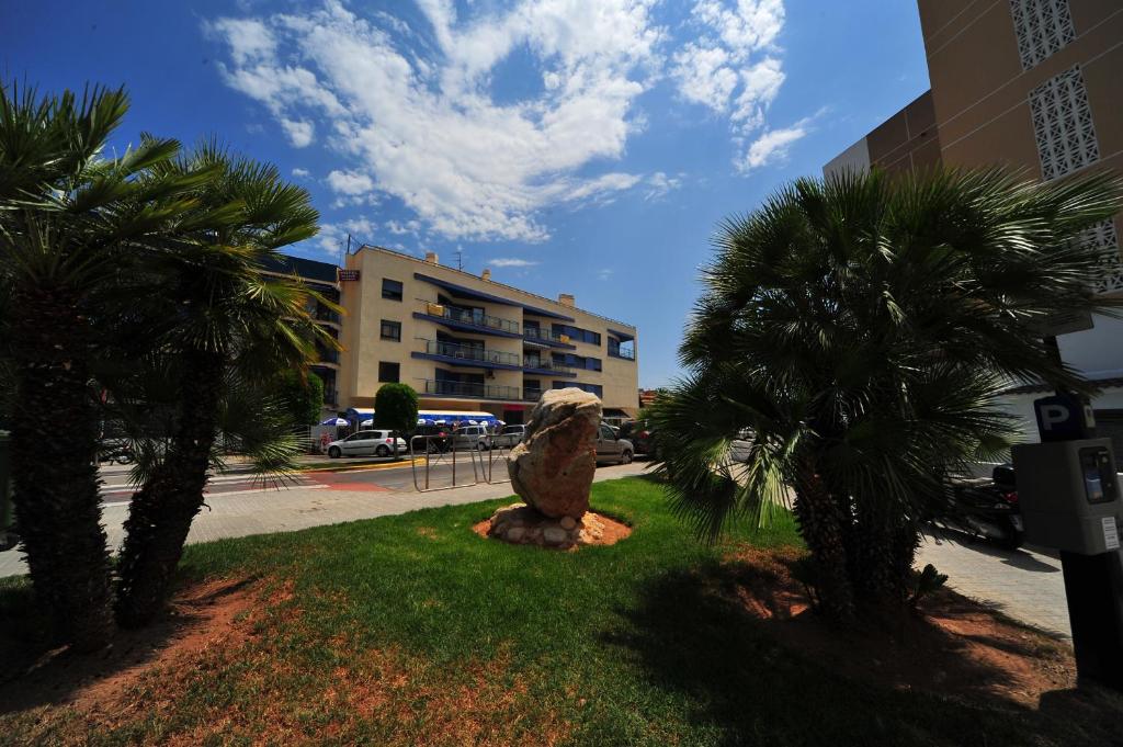 a statue of a lion sitting in the grass next to palm trees at Dos Bahías Orangecosta in Peniscola