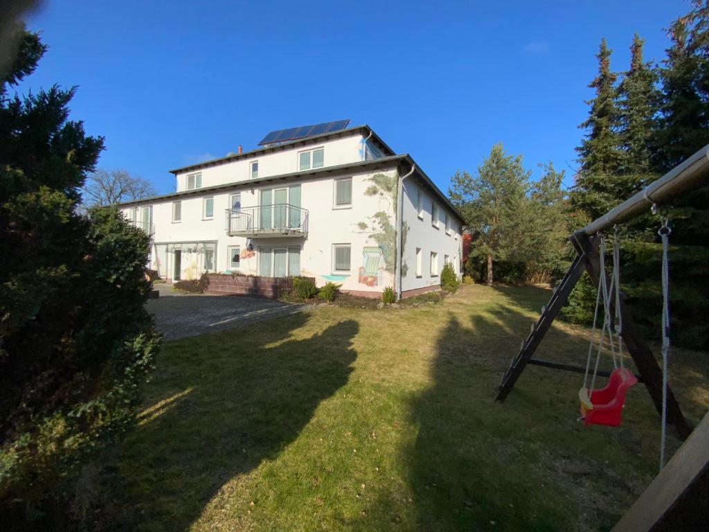 una gran casa blanca con un columpio delante de ella en Zur Alten Tischlerei, en Ostseebad Karlshagen