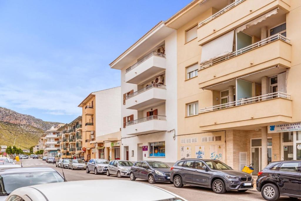 una strada con auto parcheggiate di fronte agli edifici di Espectacular Apartamento a Port de Pollença