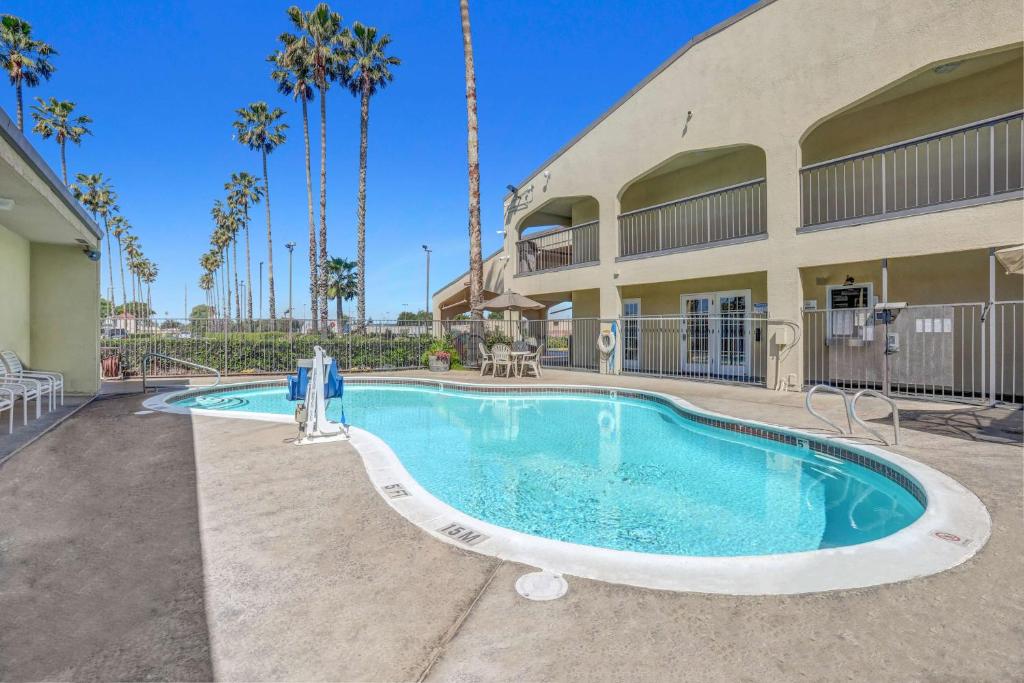 a swimming pool in front of a building with palm trees at Motel 6-Lodi, CA in Lodi