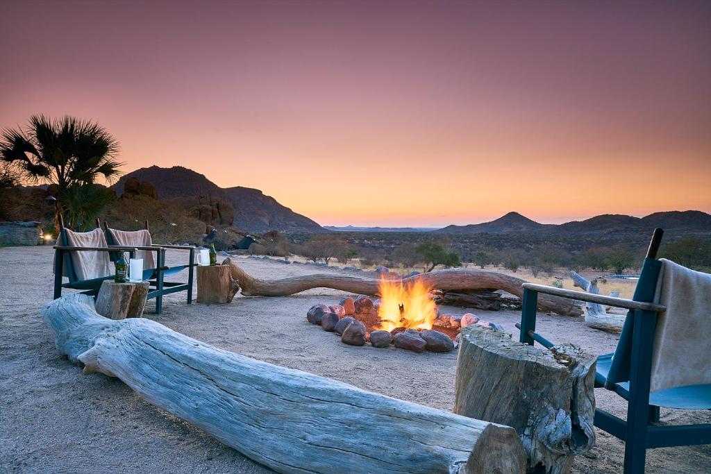 a fire pit in the desert at sunset at Ai Aiba - The Rock Painting Lodge in Omaruru