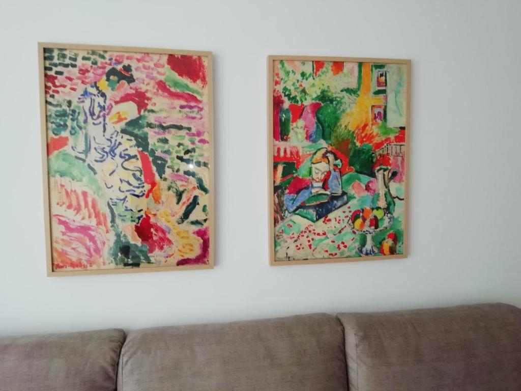 two paintings hanging on a wall next to a couch at Apartamento Conlledo in Villaviciosa