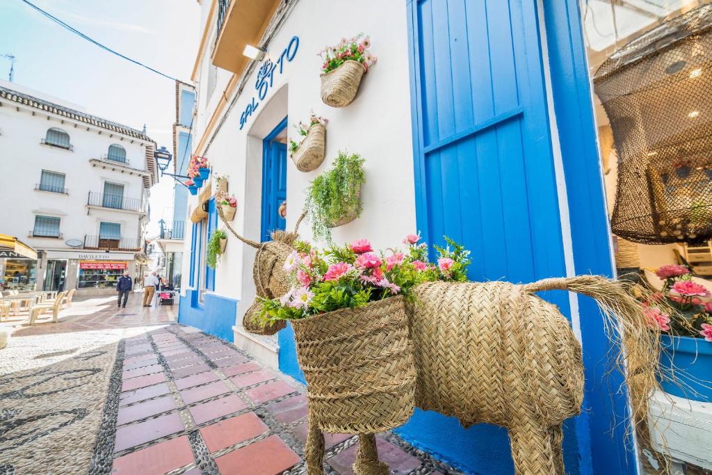 a blue door and baskets of flowers on a narrow street at Óbal Hotel Marbella in Marbella