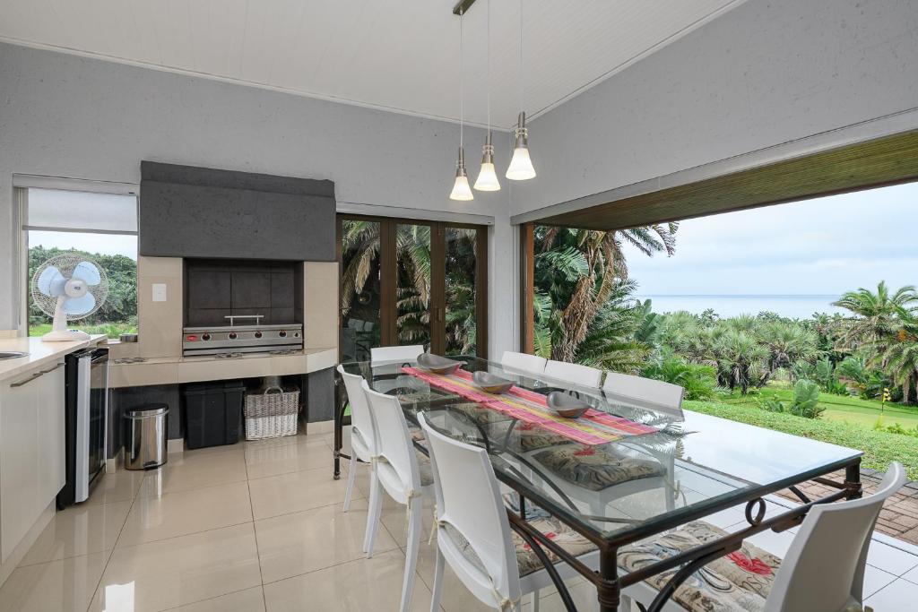 a kitchen and dining room with a glass table and chairs at San Lameer Villa 3706 - 4 Bedroom Superior - 8 pax - San Lameer Rental Agency in Southbroom
