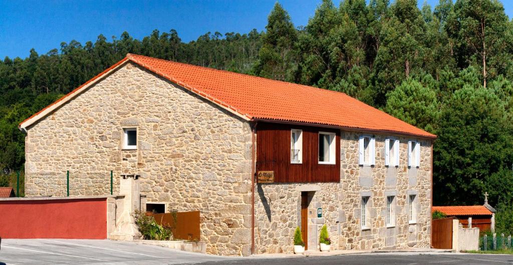 un gran edificio de piedra con techo naranja en A Casa do Folgo Turismo Rural, en Negreira