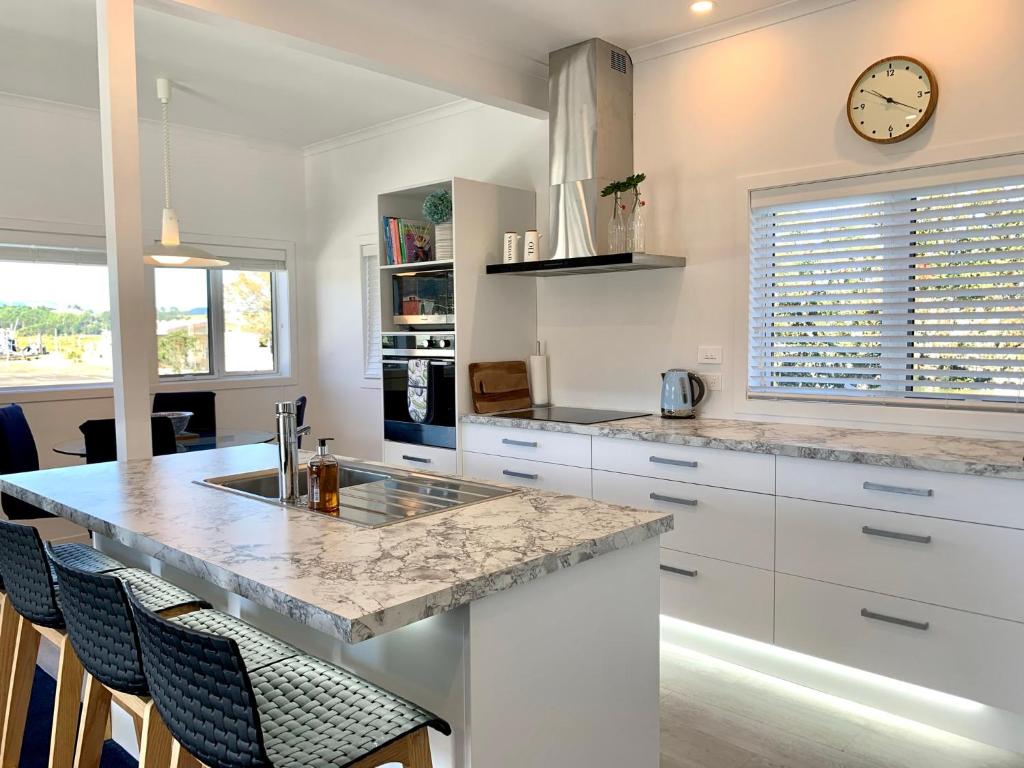 a kitchen with a counter and a clock on the wall at Coromandel Town Harbourside Cottage Luxury Accommodation in Coromandel Town