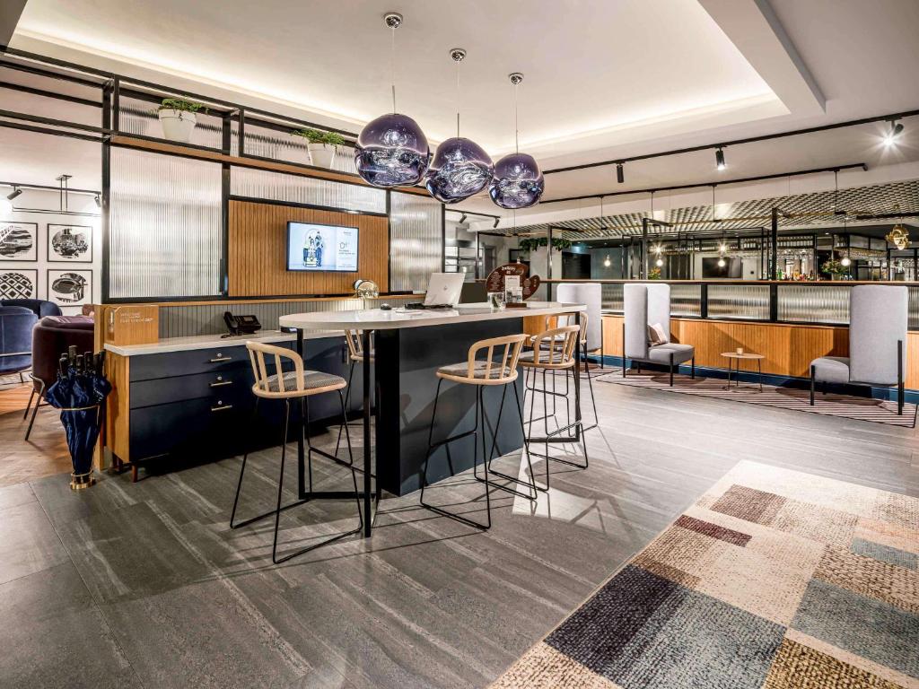 a kitchen with a bar with stools at Novotel Den Haag City Centre, fully renovated in The Hague