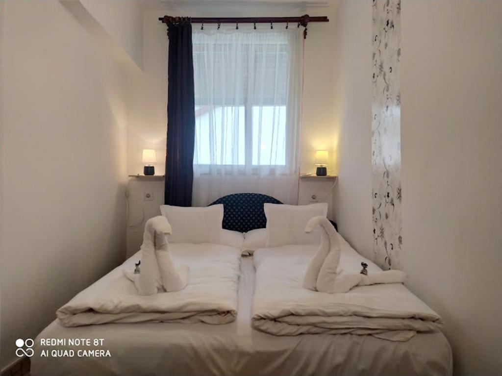 ハイドゥソボスローにあるMarabella Apartmanokのベッドルーム1室(白いシーツ付きのベッド1台、窓付)