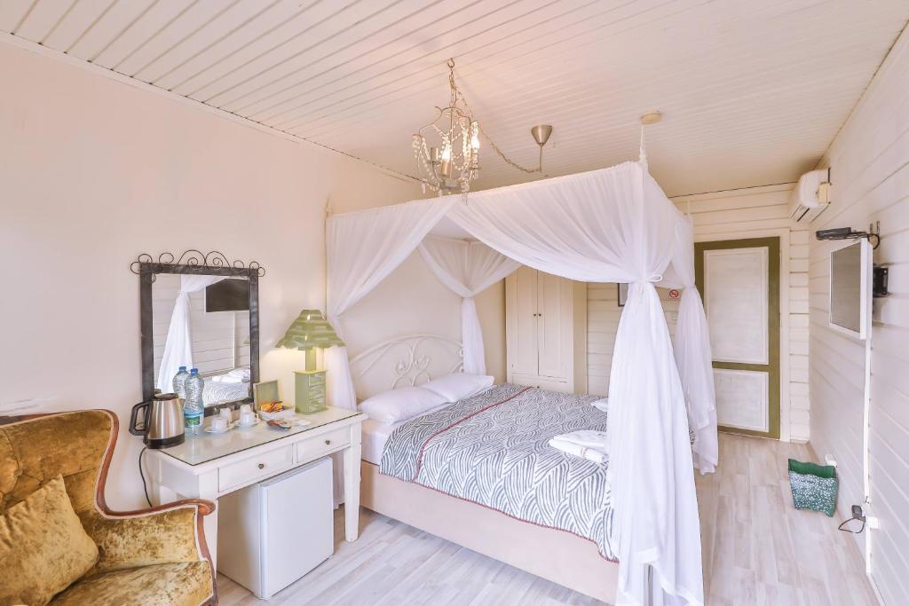 a bedroom with a canopy bed with a desk and a mirror at Park Mandalin Hotel - Adult only in Ağva