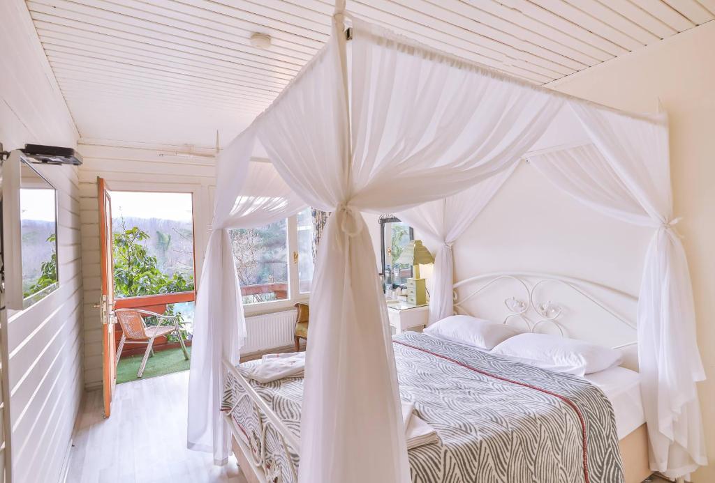 a bedroom with a white canopy bed and a balcony at Park Mandalin Hotel - Adult only in Ağva