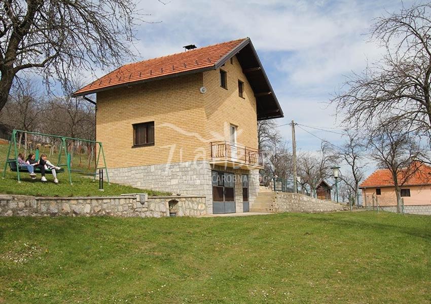 two people sitting on a swing in front of a building at VILA ANTONIJE in Šljivovica