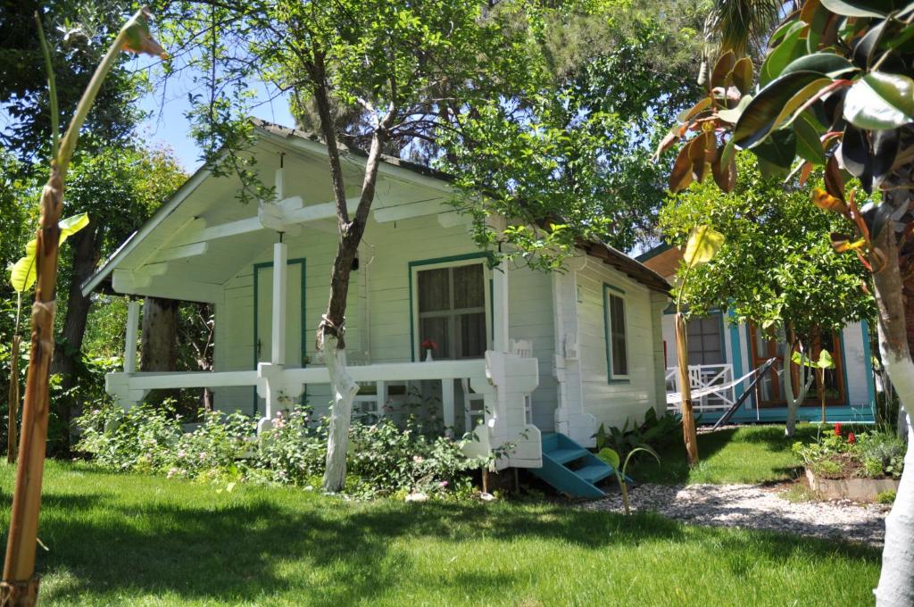 a small white house in the middle of a yard at Bellerofon Beach Otel in Cıralı