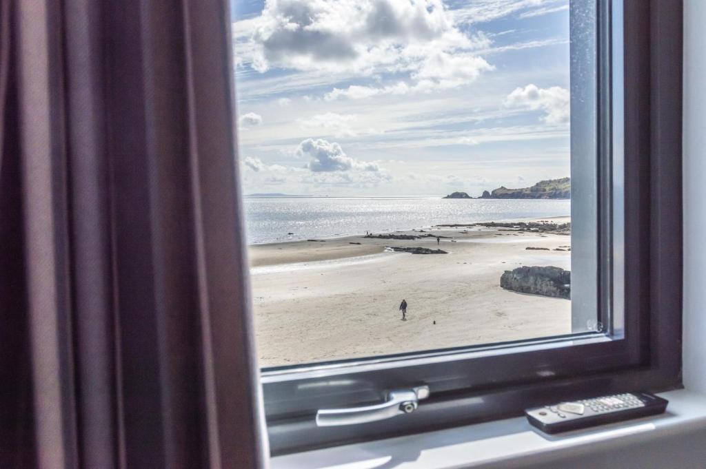 a view of a beach from a window at No 2 Ocean Cabins - Saundersfoot Harbour - Saundersfoot in Saundersfoot