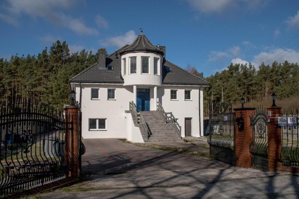a white house with a black roof and a gate at Villa Eryka in Świnoujście