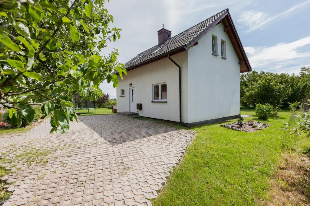 a small white house with a brick driveway at Dom Wakacyjny Kurnik by Renters in Kołczewo