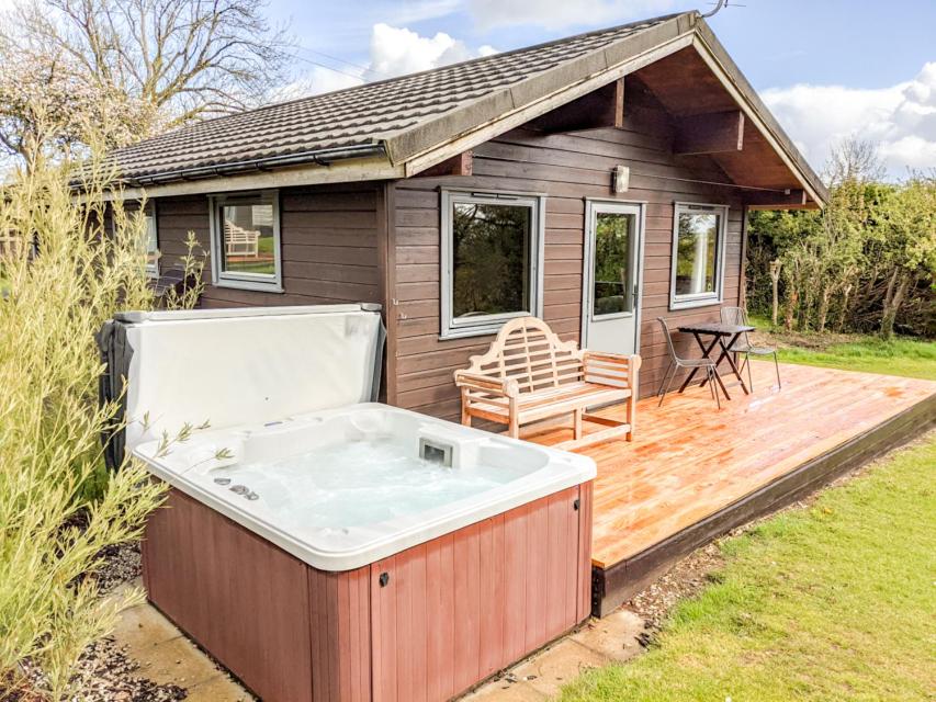 una bañera de hidromasaje en una terraza de madera con una casa en Avallon Lodges, en Launceston