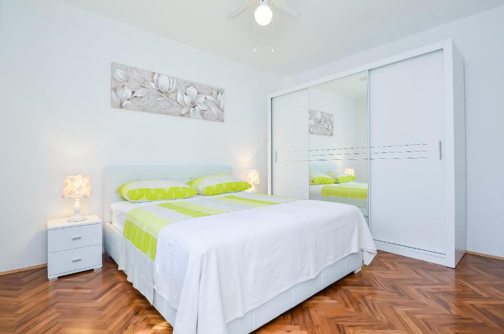 a white bedroom with a bed and a sliding glass door at Studios Heliva in Dubrovnik
