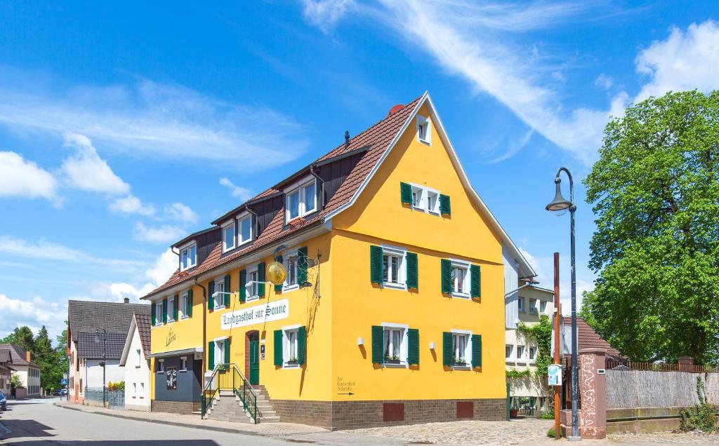 a yellow building with a brown roof on a street at Landgasthof zur Sonne in Auggen