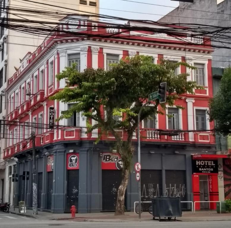 un edificio rojo y blanco con un árbol delante de él en Hotel Santos, en Santos